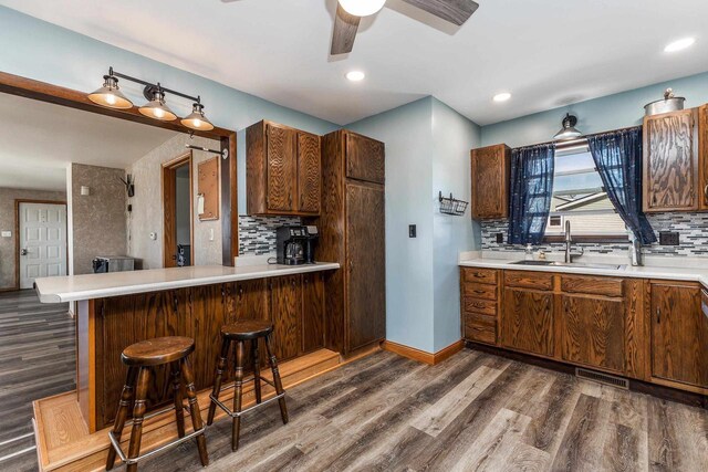 kitchen featuring light countertops, dark wood-type flooring, baseboards, and a sink