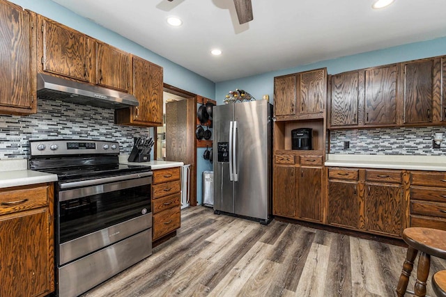 kitchen with under cabinet range hood, light wood-style flooring, stainless steel appliances, and light countertops