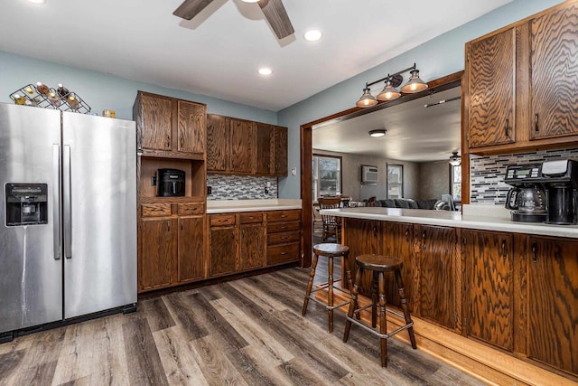 kitchen featuring a ceiling fan, dark wood-style floors, light countertops, stainless steel refrigerator with ice dispenser, and tasteful backsplash