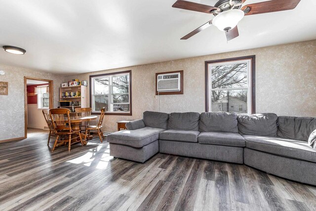 living area featuring wood finished floors, baseboards, a wall mounted air conditioner, and ceiling fan