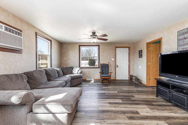 living area with an AC wall unit, wood finished floors, and a ceiling fan