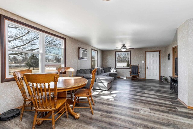 dining space with wallpapered walls, wood finished floors, a ceiling fan, and a wall unit AC