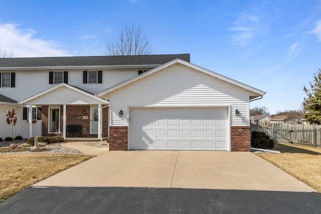 traditional-style home with a garage, brick siding, driveway, and fence