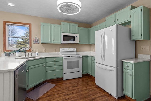 kitchen with dark wood finished floors, white appliances, light countertops, and a sink