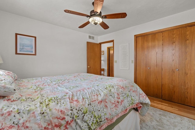 bedroom with a closet, visible vents, a ceiling fan, and wood finished floors