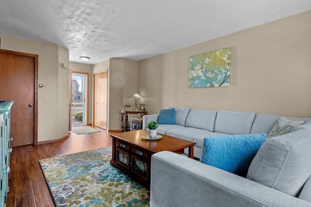 living area with a textured ceiling, baseboards, and wood finished floors