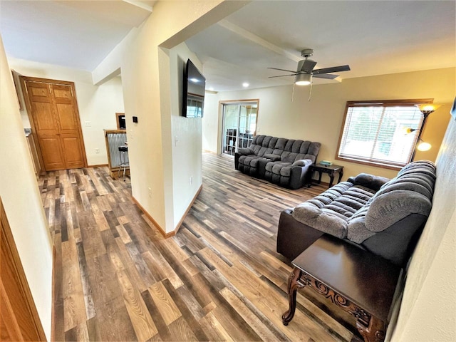 living area featuring baseboards, wood finished floors, and a ceiling fan