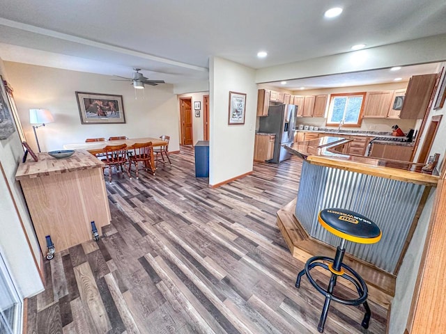 kitchen with wood finished floors, recessed lighting, a peninsula, stainless steel fridge with ice dispenser, and baseboards