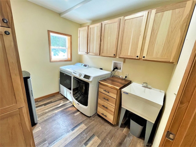 laundry room featuring washing machine and clothes dryer, cabinet space, baseboards, and light wood-style floors