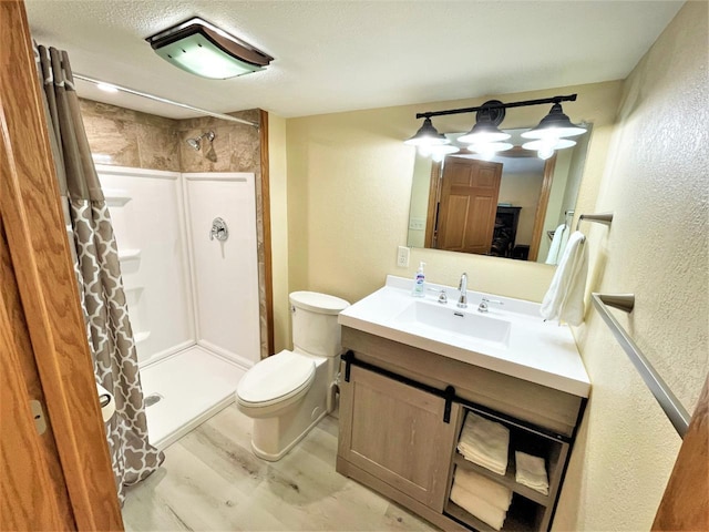 full bath with vanity, wood finished floors, a stall shower, toilet, and a textured wall