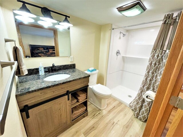 full bath featuring vanity, a shower stall, toilet, and wood finished floors