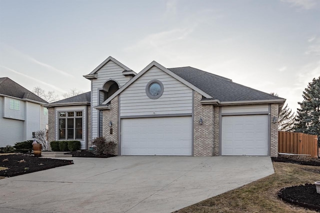 view of front facade with fence, driveway, roof with shingles, a garage, and brick siding