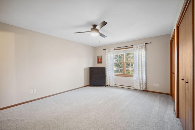 unfurnished bedroom featuring light carpet, a ceiling fan, a baseboard heating unit, a closet, and baseboards