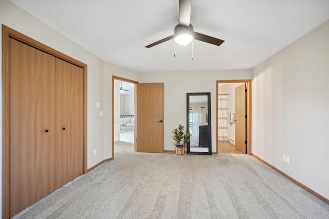 unfurnished bedroom with baseboards, carpet floors, a closet, ensuite bath, and a ceiling fan