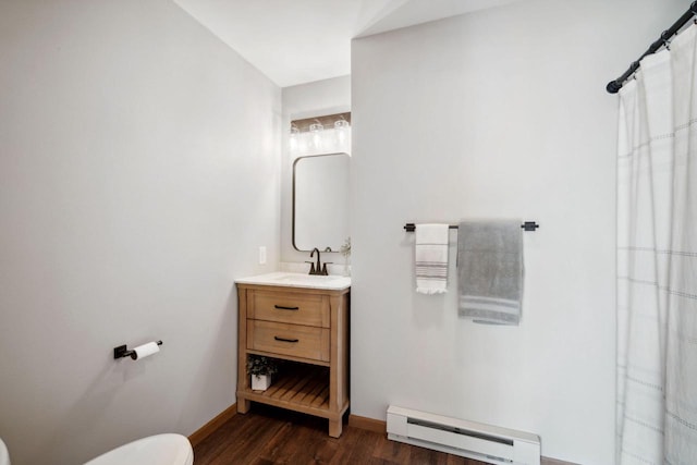 full bathroom with vanity, wood finished floors, baseboards, toilet, and baseboard heating