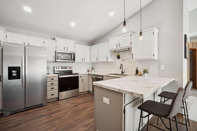 kitchen with appliances with stainless steel finishes, white cabinetry, a peninsula, and a sink