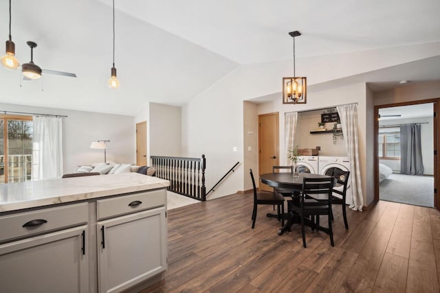 dining area featuring a wealth of natural light, independent washer and dryer, dark wood-type flooring, and vaulted ceiling