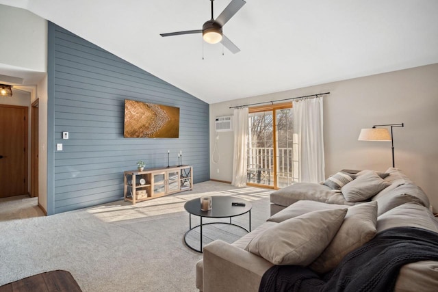 carpeted living room with an accent wall, lofted ceiling, wooden walls, and ceiling fan