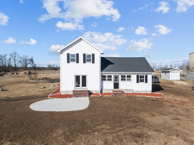 back of property with entry steps, a shingled roof, and a yard