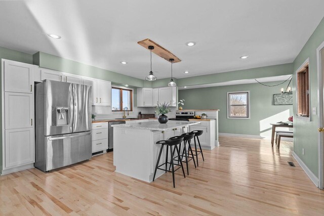 kitchen with a breakfast bar, light wood-style flooring, appliances with stainless steel finishes, and a center island