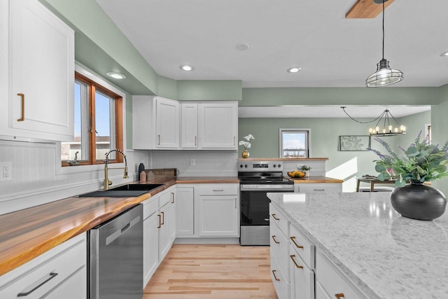 kitchen with wooden counters, white cabinets, appliances with stainless steel finishes, and a sink