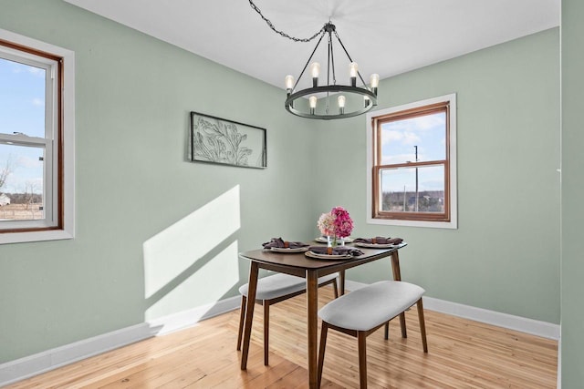 dining area featuring baseboards, light wood-style floors, and an inviting chandelier