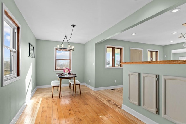 dining room featuring baseboards, plenty of natural light, an inviting chandelier, and light wood finished floors