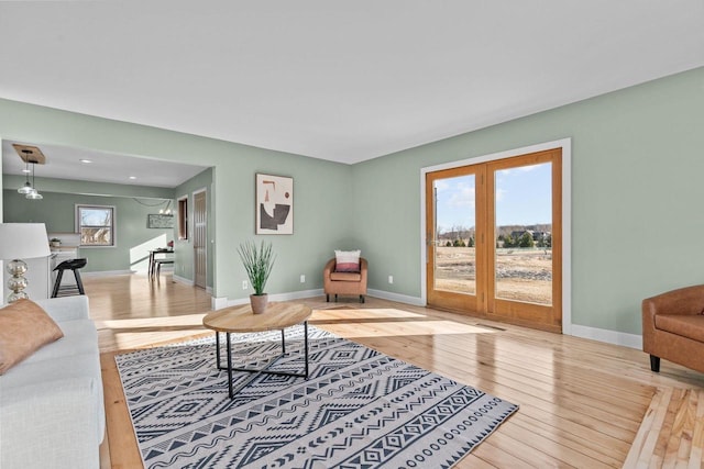 living area featuring french doors, baseboards, and wood-type flooring