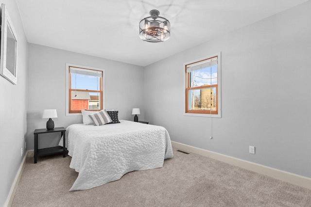 carpeted bedroom featuring visible vents, multiple windows, and baseboards