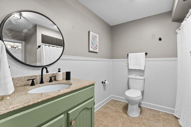 full bathroom with vanity, toilet, a wainscoted wall, and tile patterned flooring