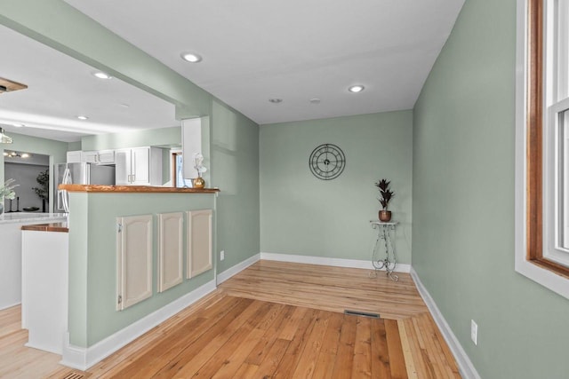 interior space featuring recessed lighting, baseboards, freestanding refrigerator, and light wood-style floors