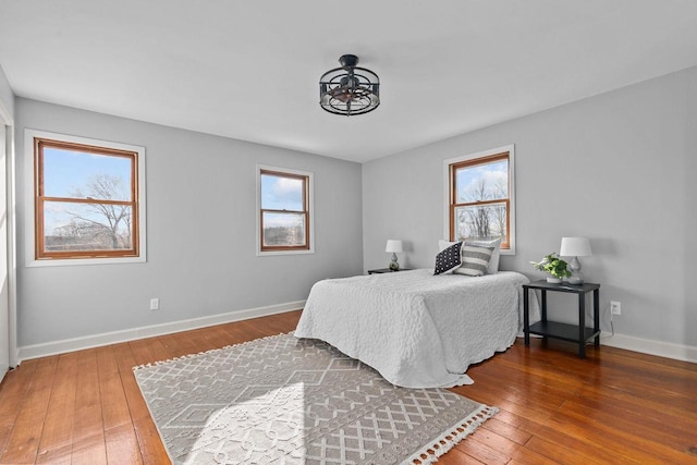 bedroom with baseboards, wood-type flooring, and multiple windows