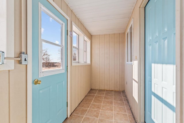 doorway to outside with wooden walls and light tile patterned flooring