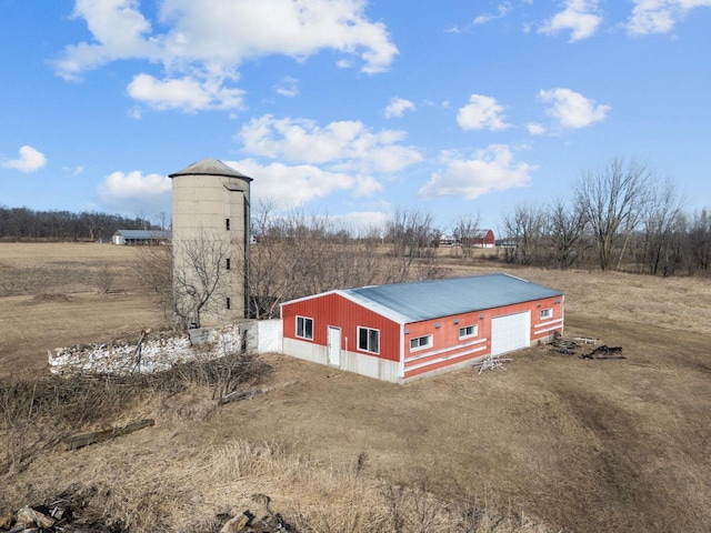 exterior space featuring metal roof, a garage, an outdoor structure, an outbuilding, and driveway