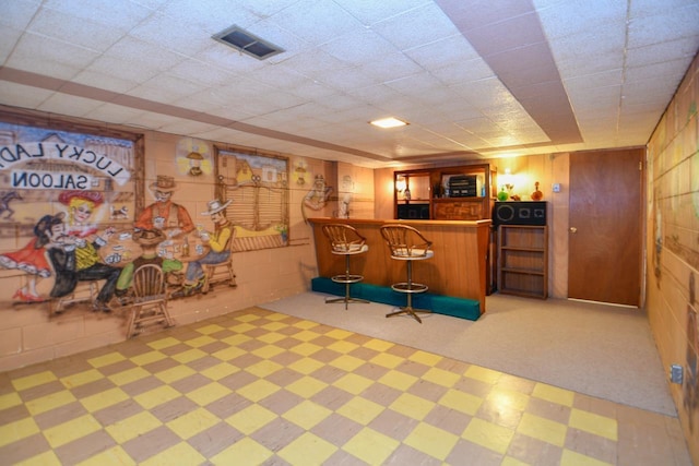 bar featuring visible vents, a bar, and concrete block wall