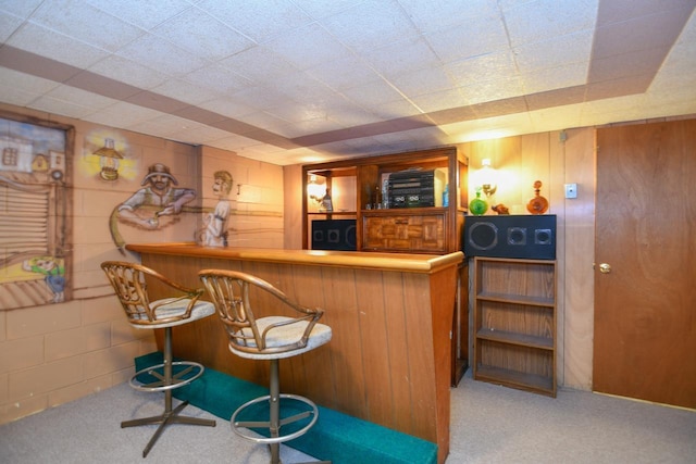 bar featuring a bar, concrete block wall, and carpet