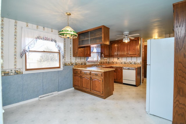 kitchen featuring white appliances, brown cabinetry, light floors, visible vents, and a peninsula