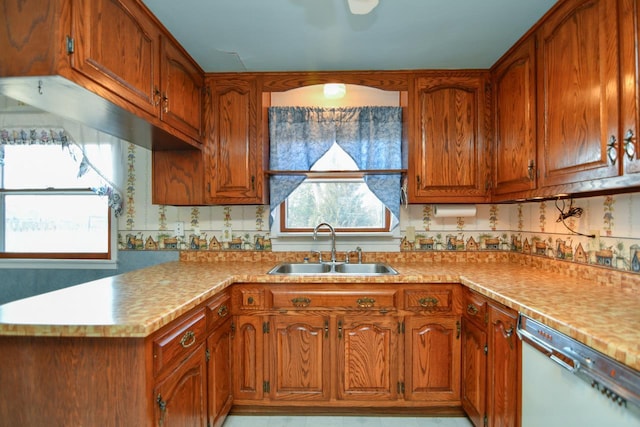 kitchen featuring brown cabinets, white dishwasher, and a sink