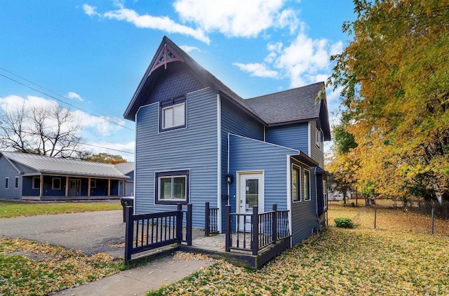 view of front of home featuring a front yard, fence, and roof with shingles