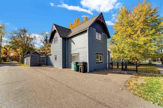 view of home's exterior with a gate, a shingled roof, and fence