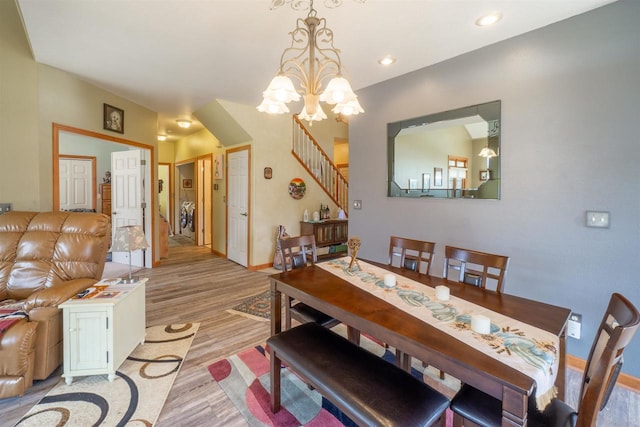 dining space featuring light wood-type flooring, recessed lighting, an inviting chandelier, baseboards, and stairs