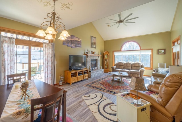 living room featuring a fireplace, ceiling fan with notable chandelier, wood finished floors, and a wealth of natural light