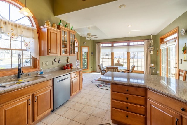 kitchen with a wealth of natural light, a sink, light tile patterned floors, and stainless steel dishwasher