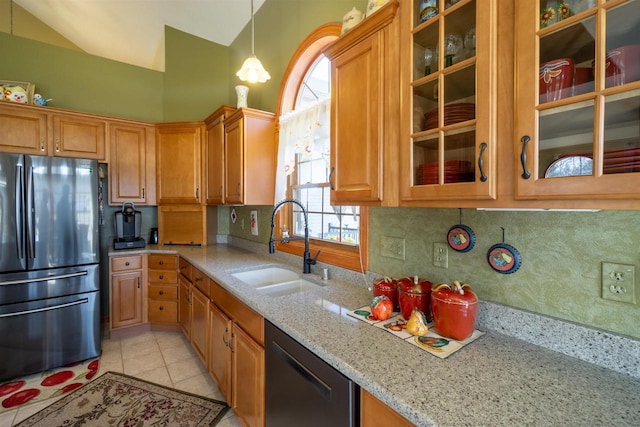 kitchen with light stone counters, dishwashing machine, decorative backsplash, freestanding refrigerator, and a sink