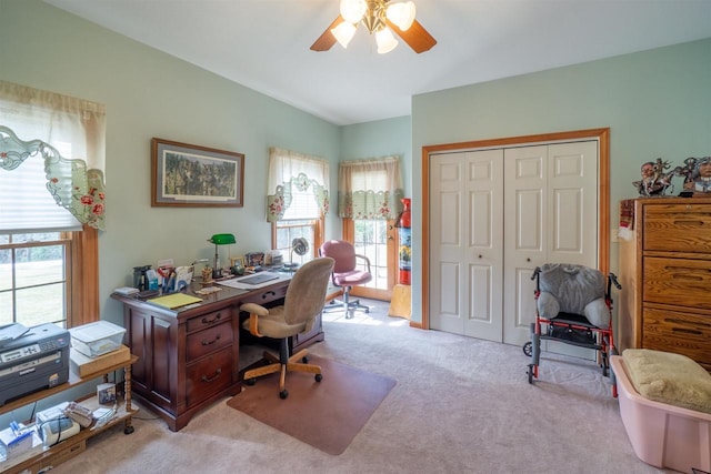 office area featuring vaulted ceiling, a ceiling fan, and light carpet