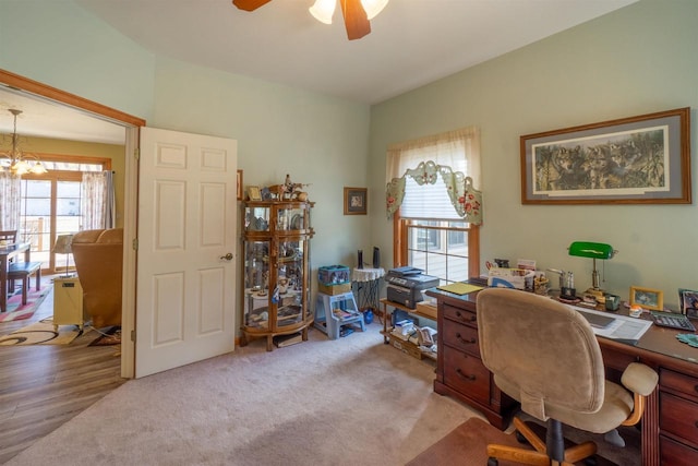 office space featuring light colored carpet and ceiling fan with notable chandelier