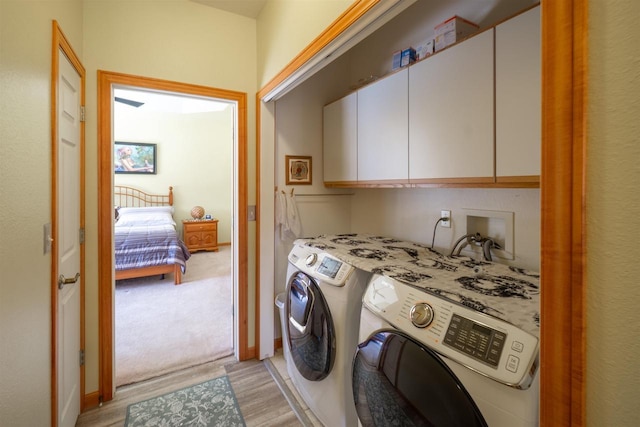 laundry room featuring independent washer and dryer, cabinet space, and light wood-style floors