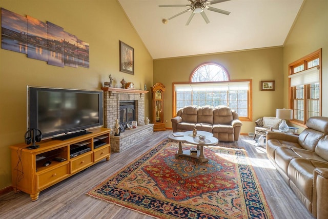 living area with baseboards, high vaulted ceiling, a brick fireplace, and wood finished floors