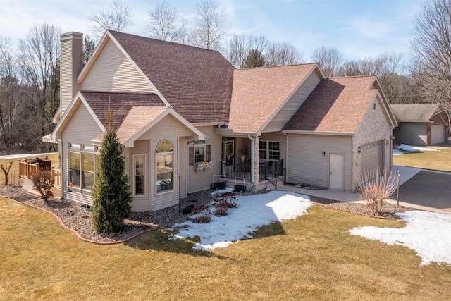 view of front of house featuring a garage, driveway, a front yard, and a shingled roof