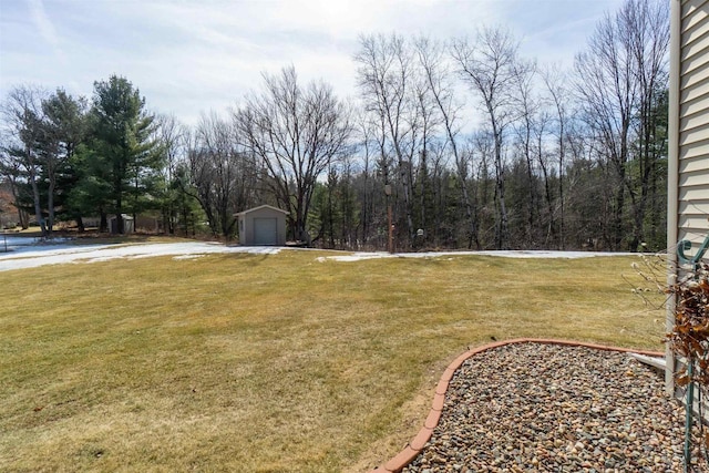 view of yard with an outdoor structure and a wooded view